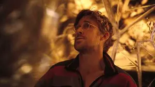 Astronaut Ryland Grace (Ryan Gosling), shaggy-haired, wearing glasses and an orange jumpsuit, in front of a crystal-faceted background