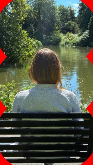 A woman sits on a bench with her back to the camera