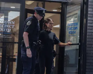 police escort a woman out of a precinct