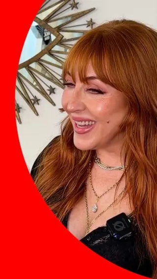 A woman with long, ginger hair smiles at someone off-camera