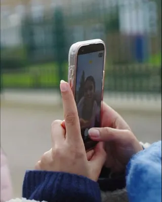 Closeup of hands using a smartphone to take an image of someone.