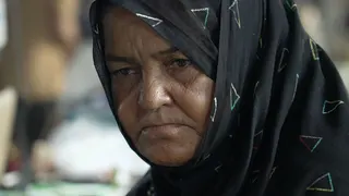 Headshot of a woman wearing a black headscarf decorated with multi-coloured triangles.