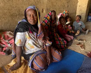 Displaced women and children sit on the ground
