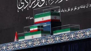 The coffins of Iran's late Supreme Leader Ayatollah Ali Khamenei and his family members in the colours of Iranian flags sit on stage at the Grand Mosalla in Tehran.