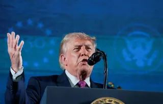 Donald Trump on stage speaking into a microphone.