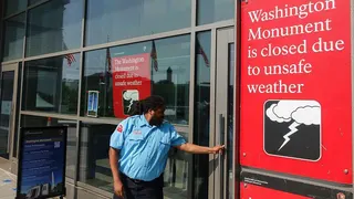 A security guard locks the door of the Washington Monument on the National Mall after it was closed during a record-setting heat wave in the region
