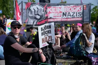 A protester sits among others with a poster that reads: 'Bjoern Hoecke is a Nazi'.