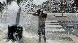 A person cools off with water from an open fire hydrant during a heat wave on the West Side of Chicago