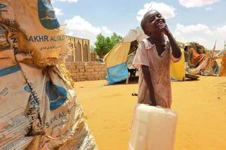 A girl laughs while carrying a plastic container
