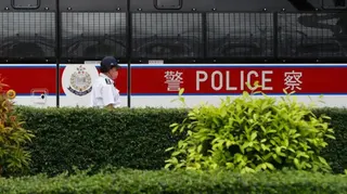 2023年6月24日，一輛警車在香港維多利亞港執勤，一名警員在警車前走過。