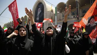 Iranians gather to grieve, with one woman crying up to the sky with her arms stretched up