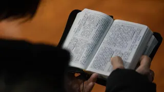 A worshipper in church holding open a Mandarin bible
