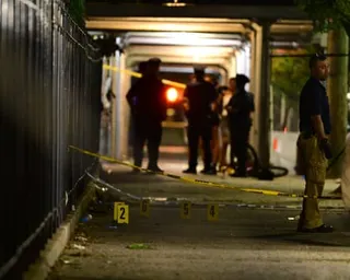 Police officers stand beside markers placed on the pavement of a street in Coney Island