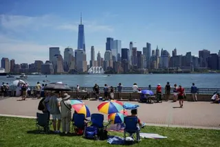 people stand by water with city skyline in background
