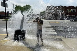 person stands by fire hydrant on sidewalk spraying water