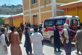 People stand near ambulances.