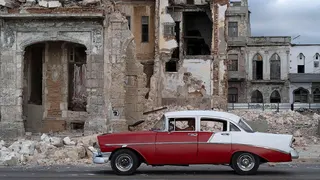An old car drives past debris from a demolished house occupying part of the seaside promenade in the Centro Habana neighbourhood in Havana on 9 June , 2026