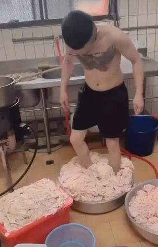 該員工裸著上身直接站進桶內，以雙腳踩踏雞皮。（圖／翻攝畫面）