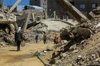 People walking along a patch cleared through the debris of destroyed buildings
