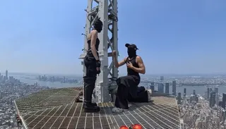 Two people appear on top of a skyscraper.