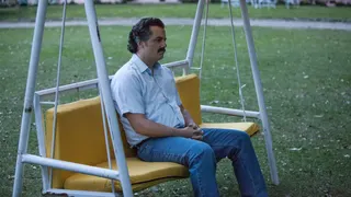A guy from Narcos sits on a bench.