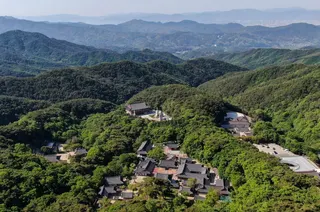 An aerial view of Donghwasa Temple, surrounded by dense woodland in the mountains near Daegu, South Korea