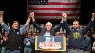 Bernie Sanders standing with Troy Jackson and Graham Platner on a stage.