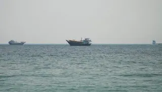 一艘船12日停在阿曼附近的荷莫茲海峽海域。(路透)