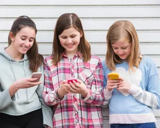 Three girls looking at their mobile phones