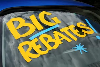 "Big Rebates" written on a new car in a dealership car lot.