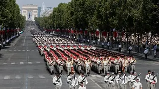 Troops march down the Champs-Elysées with the Arc de Triomphe in the background