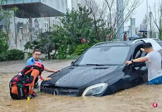 暴雨星期一（7月13日）席卷拥有近千万人口的中国东北沈阳市全域，主城区出现大面积严重积水。图为沈阳警察和消防员正在一起救助被困车辆。 （新华社）