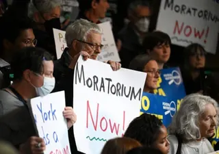 a group of people holding signs protesting against AI datacenters, such as 'moratorium now!'