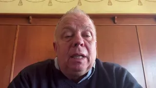 John Stiles is seen on a video link, talking to a reporter. He is middle-aged, has short light-coloured hair, and is wearing a shirt and jumper