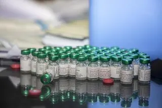 在疫苗接种活动期间，一排排带有绿色瓶盖的 Cervarix HPV 疫苗瓶被展示在反光表面上。