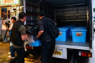 Police officers load confiscated items from independent bookstore Have A Nice Stay.