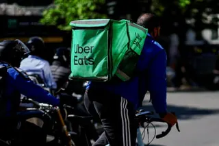 An Uber Eats courier on a bicycle with a logo backpack on his back