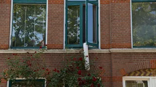 A portable air-conditioning unit's exhaust pipe hangs out of a window
