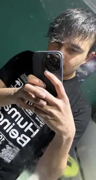 Young British-Bangladeshi man holding phone up covering his face