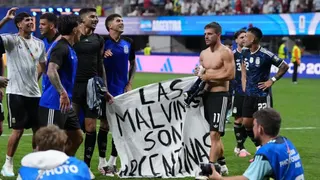 Several Argentinian football players standing on a pitch holding a banner saying "Las Malvinas Son Argentinas"