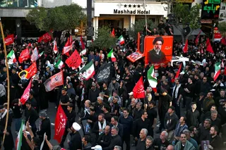 Crowds of mourners gather on a street around a portrait of Iran's supreme leader Mojtaba Khamenei ahead of the funeral procession of his father and predecessor, Ali Khamenei