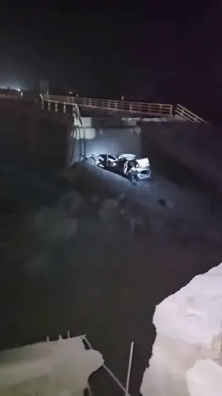 A light shines on a damaged vehicle and a collapsed portion of a bridge in the aftermath of a strike, in Bandar Khamir, Hormozgan province, Iran July 16, 2026 in this screen grab obtained from social media video. Social Media/via REUTERS  THIS IMAGE HAS BEEN SUPPLIED BY A THIRD PARTY. NO RESALES. NO ARCHIVES. NEWS USE ONLY.

VERIFICATION
- Broken railing on the bridge and vehicle from corroborating and media footage.
- Road layout, land mound and electricity pylons as seen on archive and satelli