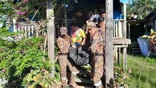 消拯员协助将遗体从河岸抬运至死者住家。