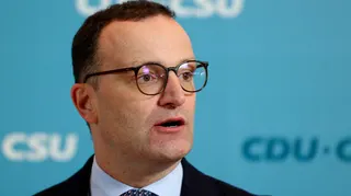 Jens Spahn speaks with German media during a party meeting, he is wearing a black suit and black glasses.