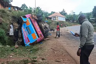 People stand near the wreckage of a bus, owned by King David Junior School, on the shoulder of the road following an accident that killed schoolchildren on the way back from an educational visit to Sipi Falls, at Chekwatit village in Kapchorwa district, Uganda, July 17, 2026. Picture taken with a mobile phone. REUTERS/Stringer