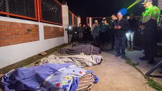 Residents stand beside covered bodies in Pumpuya, Peru.