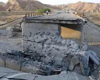 cars on road in distance by crumbled bridge