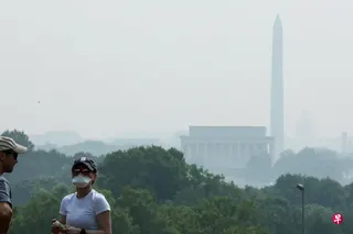 加拿大野火的烟霾飘至美国东北部大片地区，首都华盛顿特区周五的天空一片橙灰。游客从荷兰钟琴塔（Netherlands Carillon ）眺望，远处的华盛顿纪念碑仅隐约可见。 （路透社）