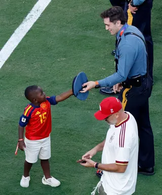A smiling policeman hands the three-year-old his hat to try on