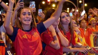 A female celebrates her country's World Cup win with her hands raised in a crowd full of Spanish supporters.
